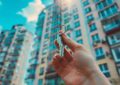 Une main tenant fièrement une clé devant un immeuble résidentiel, symbolisant la réussite de l'achat d'un premier appartement à Montpellier