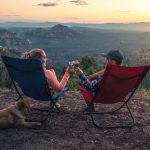 two person sitting on camping chairs while watching mountain