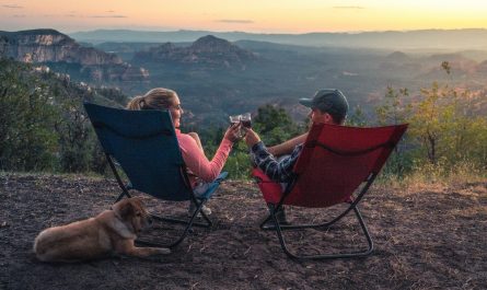 two person sitting on camping chairs while watching mountain