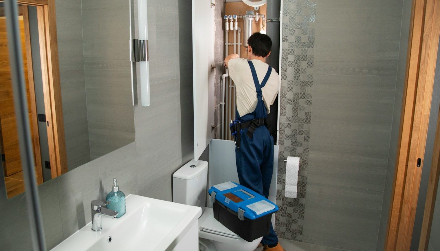 A plumber repairs plumbing in a bathroom.