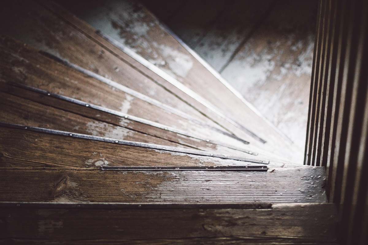 Escalier en bois usé, marches fendues, lumière entrant d'un côté