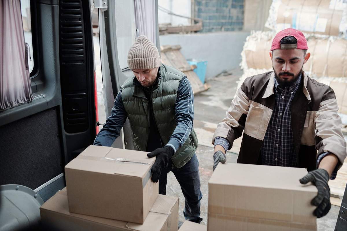 Homme décharge des boîtes d'un camion dans un entrepôt Homme décharge des boîtes d'un camion dans un entrepôt