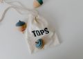 Un sac à dessin blanc contenant trois toupies colorées sur fond blanc