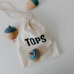 Un sac à dessin blanc contenant trois toupies colorées sur fond blanc