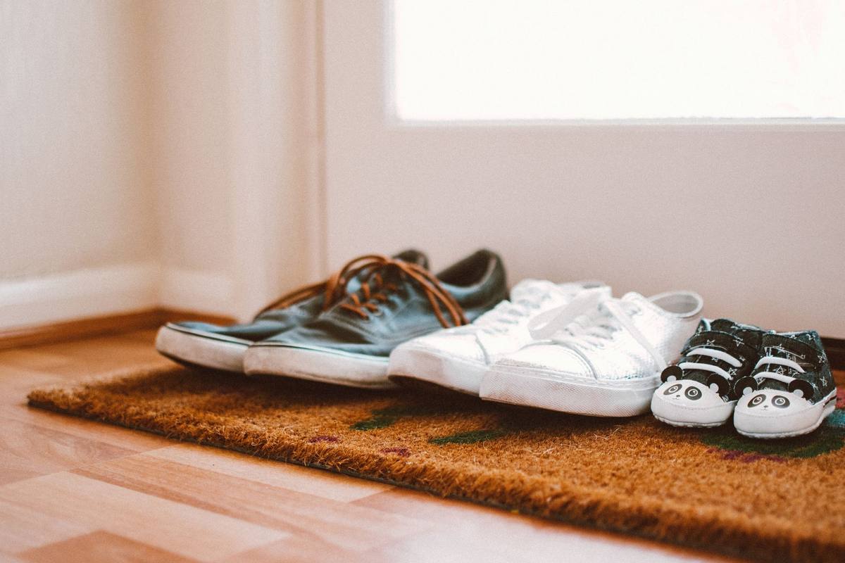 Chaussures de différents styles posées sur un paillasson près d'une porte