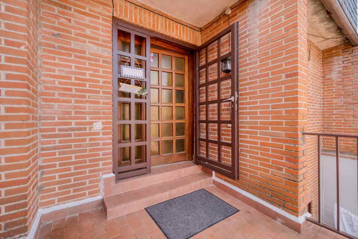 Vue d'une porte en bois avec vitraux, escalier et tapis d'entrée